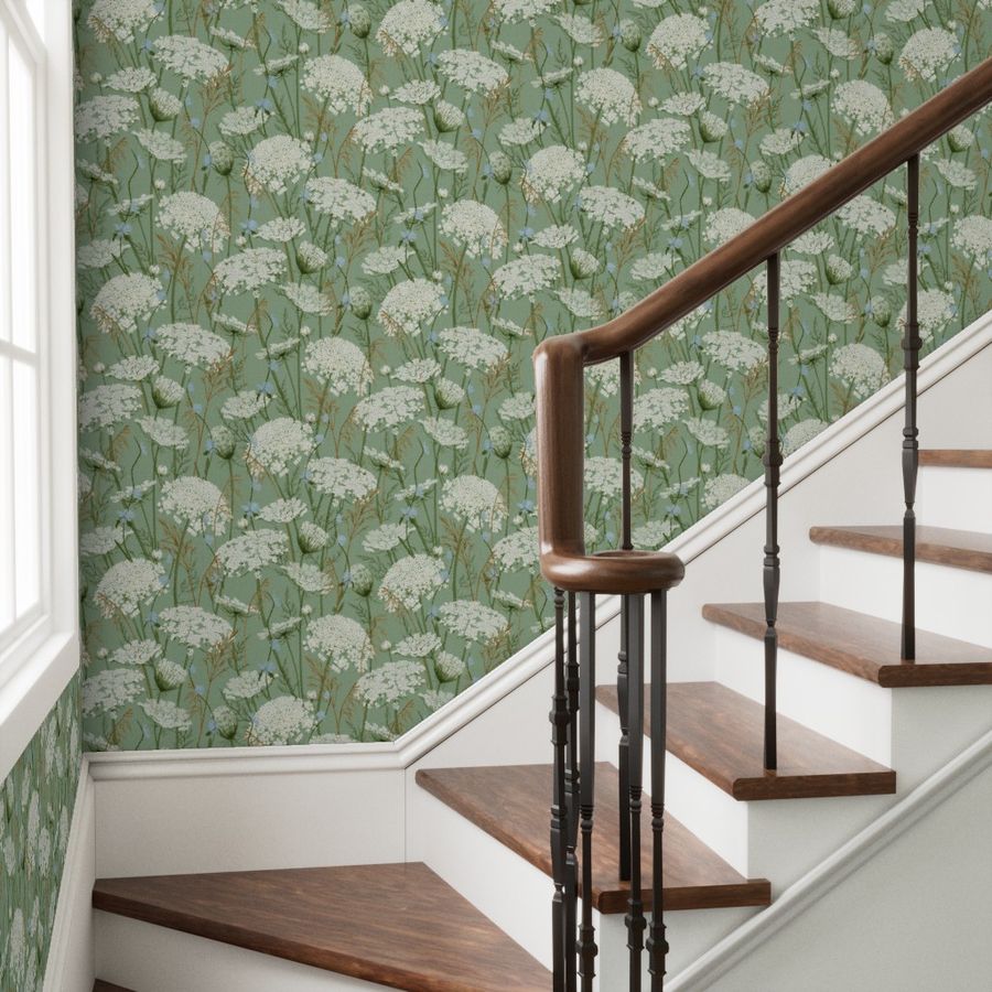 Green and white floral wallpaper on a staircase wall behind wooden steps with a dark wood railing.