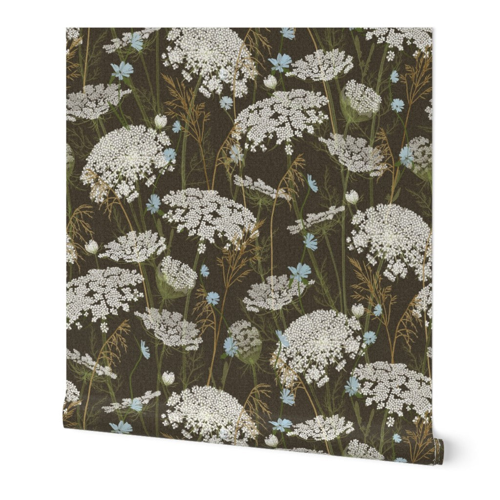 A roll of wallpaper featuring a dark brown background with a repeating floral pattern of white Queen Anne's lace and small light blue flowers, shown against a plain white background.